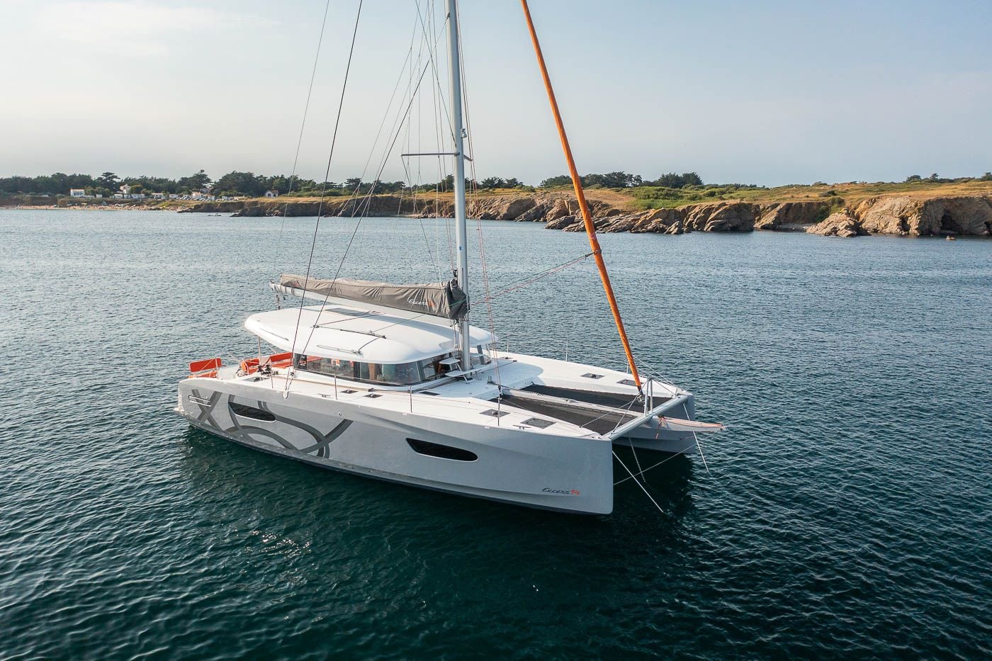 Le catamaran Excess 14 AGAPE au mouillage le long d'une côte rocheuse