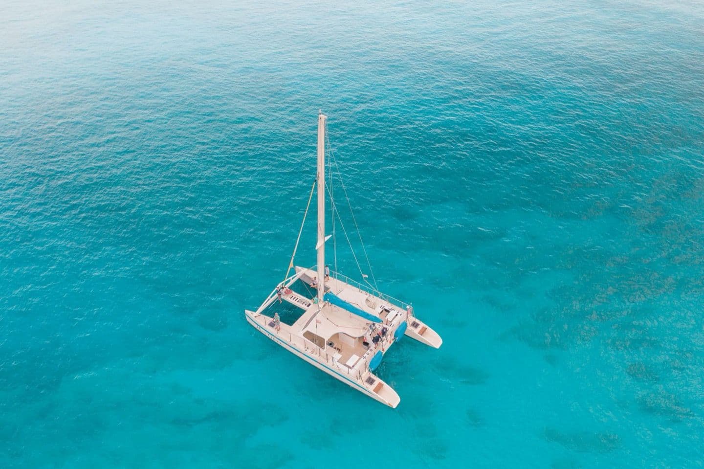 Catamaran à voile avec passagers au mouillage sur une eau turquoise, sortie sans permis avec skipper