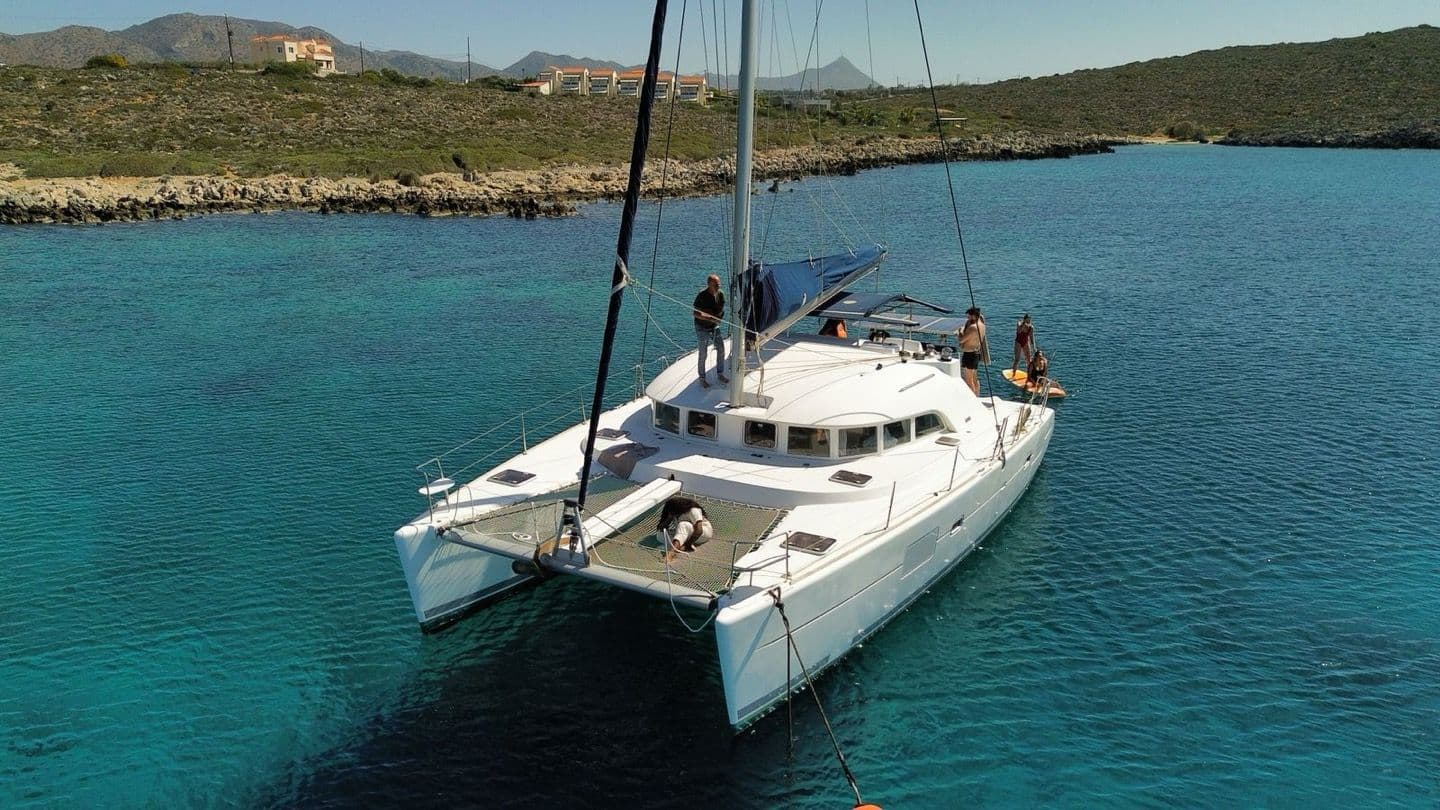 Catamaran à voile au mouillage dans une crique turquoise, passagers à bord, sortie sans permis avec skipper vers Porquerolles