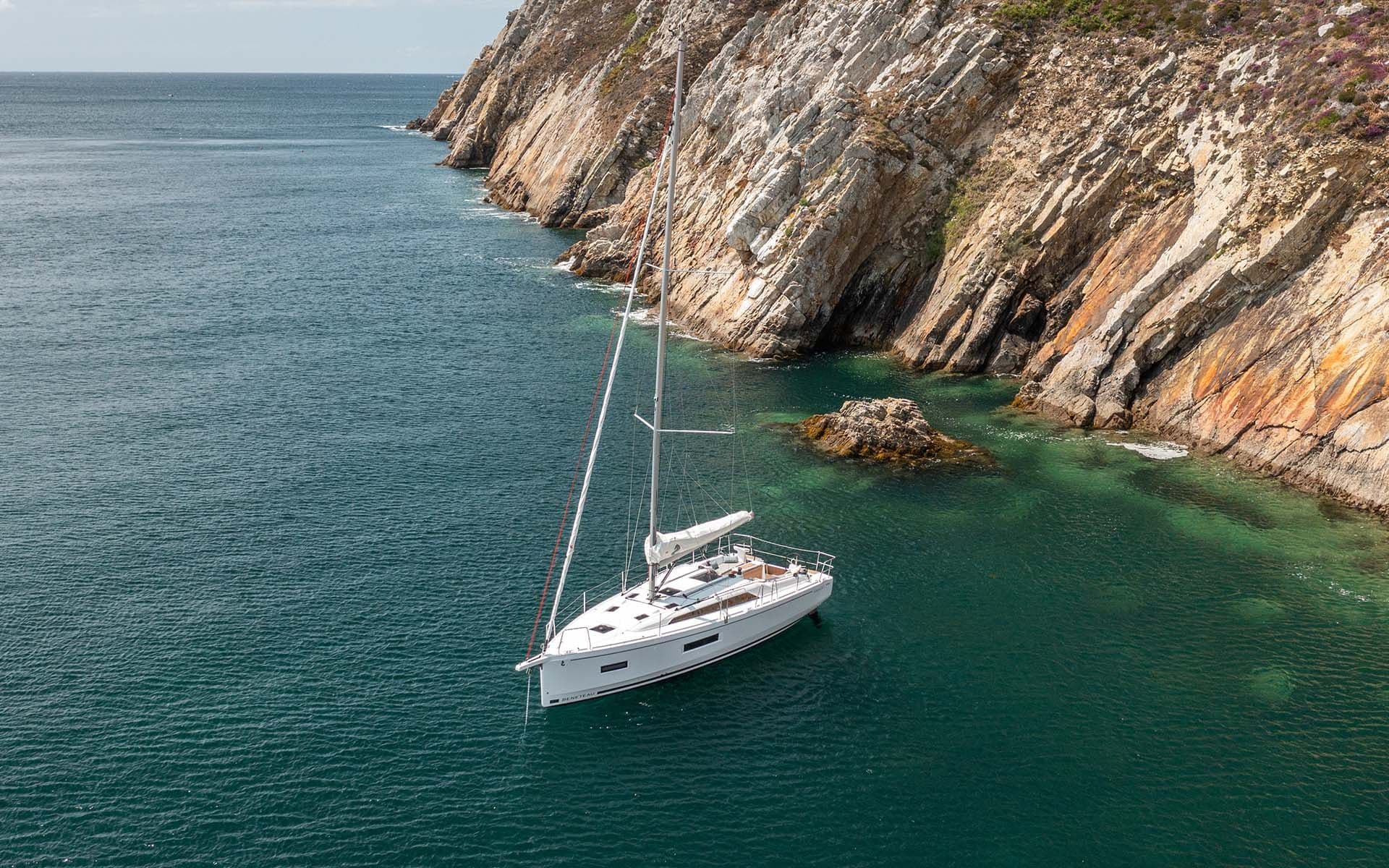 Le voilier Oceanis 37.1 ALBA au mouillage en eau turquoise au pied d'une falaise