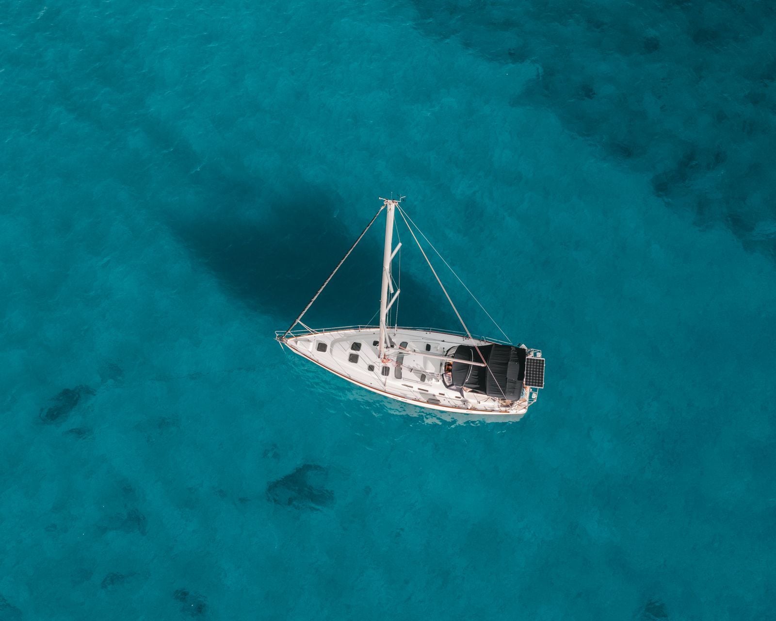 Voilier au mouillage vu du ciel sur une eau turquoise, fond de sable et d'herbier Voilier au mouillage vu du ciel sur une eau turquoise, fond de sable et d'herbier