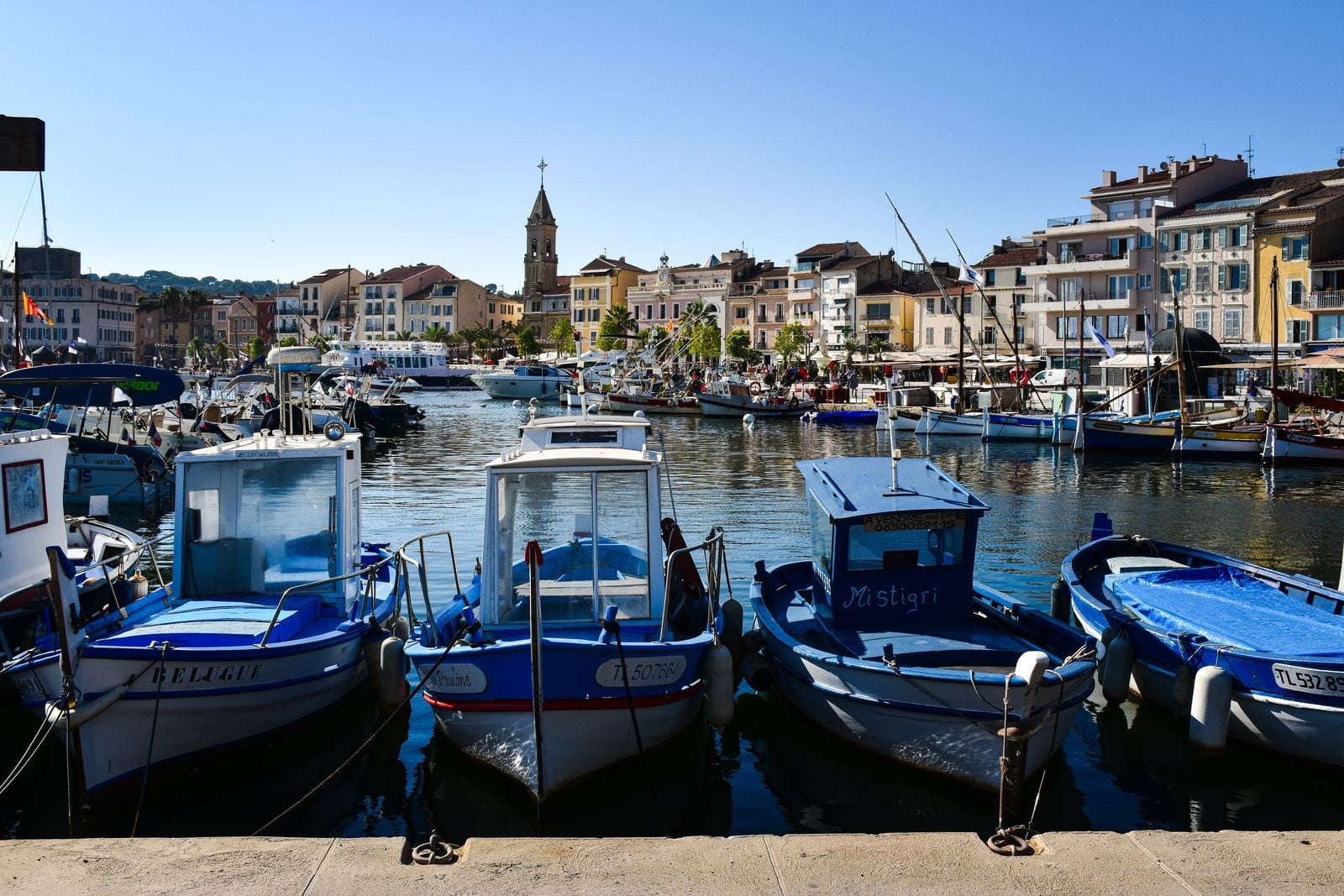 Pointus bleus amarrés au quai du port de Sanary, le clocher en arrière-plan Pointus bleus amarrés au quai du port de Sanary, le clocher en arrière-plan